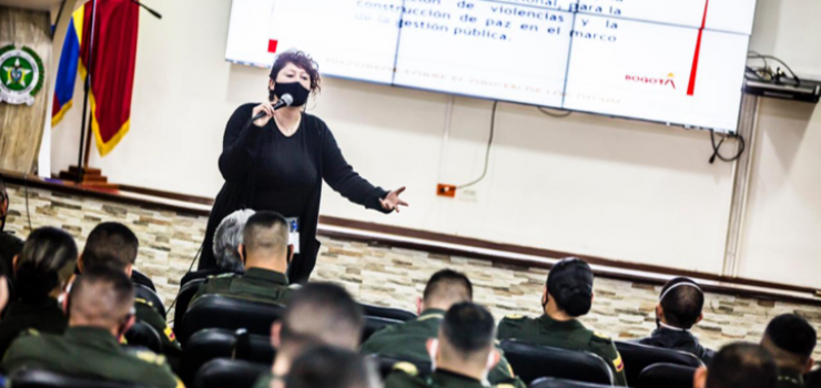 Foto de Mujer con tapabocas hablando en auditorio a un grupo de policías La Secretaria de Gobierno capacita en Derechos Humanos a miembros de la policía que trabajan en sectores donde se ejercen actividades sexuales pagadas.